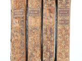 trois vieux livres posés l'un sur l'autre sur une surface blanche