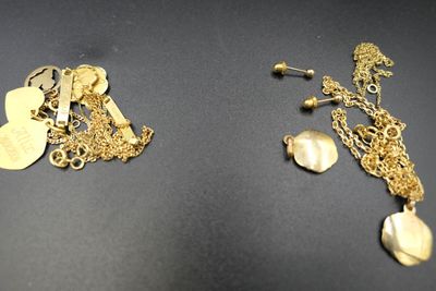 Deux bijoux en or sont posés sur une surface noire