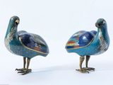 une paire de figurines d'oiseaux bleues et dorées posées sur un fond blanc