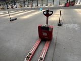 a red forklift sitting in a warehouse with a red fork
