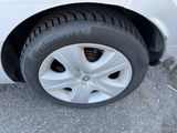 a white car that has a tire on the side of the road