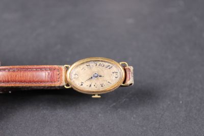 an old wrist watch with a brown leather band on a black surface