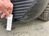 a man that is holding a piece of paper in front of a car