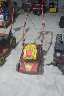 Plusieurs tondeuses à gazon sont alignées les unes à côté des autres dans un garage