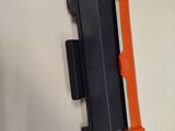 a close up of a black and orange toner on a white surface