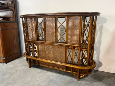 un grand meuble de style rotin dans une pièce avec un piano en arrière-plan