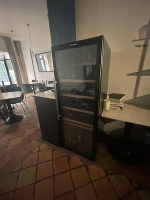 un réfrigérateur au milieu d'une pièce où se trouvent une table et des chaises