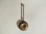 an old brass clock with a pendulum on a white wall