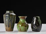 three vases sitting on a white table with a black background