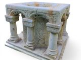 a small stone structure with columns on it