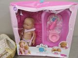 a baby doll in a pink box next to a pair of shoes