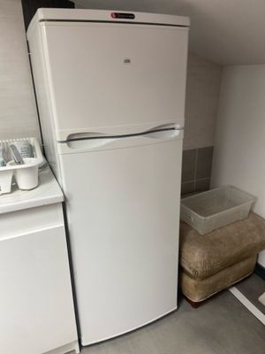 a white refrigerator in the corner of a small kitchen