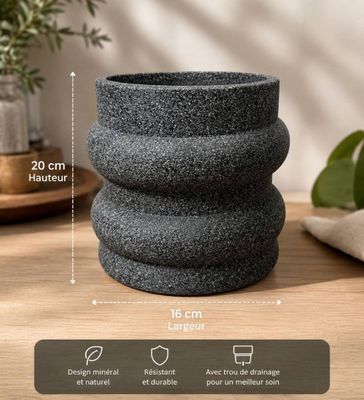 un gros plan d'une jardinière posée sur une table, avec une plante en arrière-plan