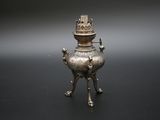 une image représentant un brûle-parfum en métal argenté surmonté d'une couronne