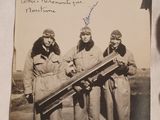 three women in military uniforms holding a large telescope in front of a building