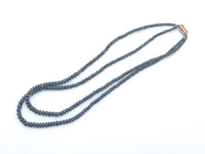 un gros plan d'un long collier de perles posé sur une surface blanche