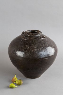 un vase noir devant lequel se trouve une petite fleur
