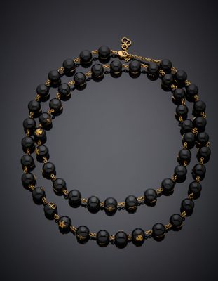 un collier en perles noires et dorées, muni d'un fermoir doré