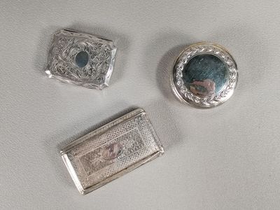three silver and blue stones sitting on top of a white surface