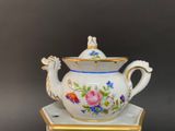 a white tea pot with a gold rim and a flower design on it