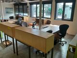 tables and chairs in an empty office with windows overlooking a street
