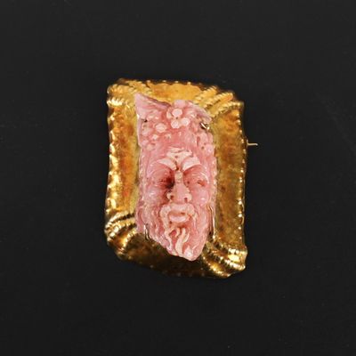 une image représentant une broche rose et dorée posée sur une surface noire