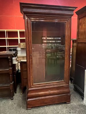 a tall wooden cabinet with a glass door in a room