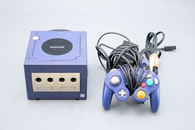 une console de jeux vidéo et une manette de jeu placées l'une à côté de l'autre