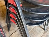 a stack of black and red chairs sitting on a wooden floor