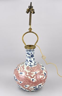 un vase rose et blanc avec une anse dorée posé sur une table