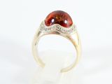 an image of a ring with a red stone and diamonds on it