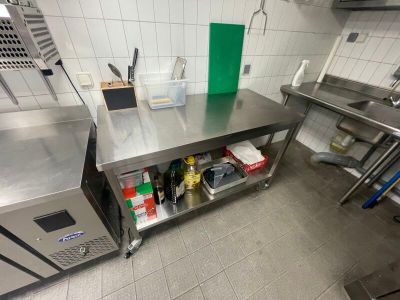 une grande table en inox dans une cuisine, sur laquelle sont disposés de nombreux objets