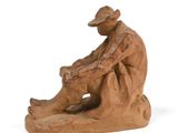 figurine of a man with a hat sitting on a rock