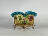 un vase en verre orné de fleurs, posé sur un socle