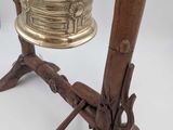 a brass vase on a stand with a wooden handle