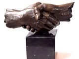 statue of two hands shaking each other on a black marble base