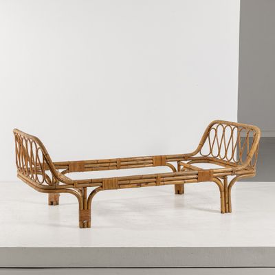 une image représentant un banc en rotin posé sur une surface blanche