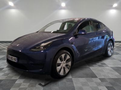 La Tesla Model Y bleue est garée dans une pièce dont le sol est en damier.