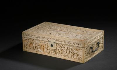une vieille boîte ornée de sculptures, posée sur une surface noire