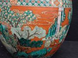 an orange vase with a painting on it on a black surface