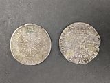 two silver coins sitting on top of a table next to each other