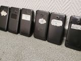 four cell phones lined up against a wall with a white wall behind them