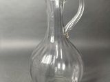 a clear glass pitcher with a handle on a table