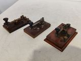 three antique steam engine models sitting on top of a white table