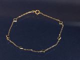 un bracelet en chaîne dorée à maillons carrés sur un fond noir