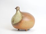 a brown and green vase sitting on a white surface