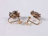 two pairs of gold and diamond earrings on a white surface