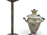 a silver urn next to a silver candle holder on a white background