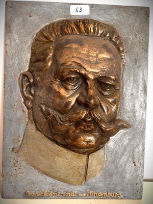 une plaque en bronze représentant un homme avec une moustache et une barbichette