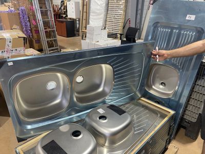 a man standing next to a metal stove with three pans inside of it